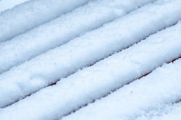 Rows of fresh white snow on wooden bench in winter. Texture of winter white snow background.