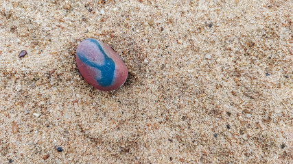 Fototapeta na wymiar selective focus on a red stone middle of the sand