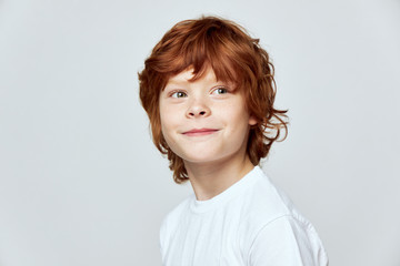 Redhead boy in white t-shirt smile cropped view gray isolated background studio