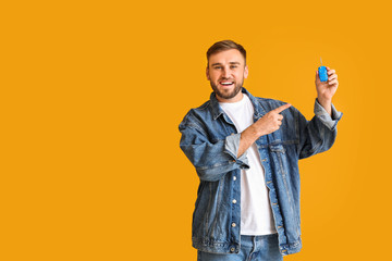 Happy young man with car key on color background