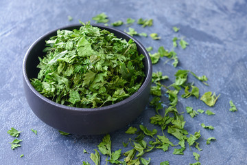 Bowl with dry parsley on dark background