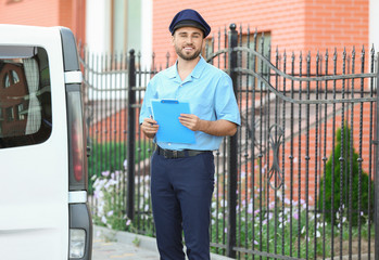 Handsome young postman near car outdoors