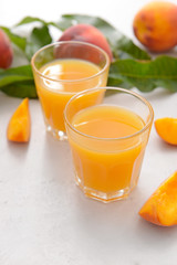 Glasses of tasty peach juice on white background