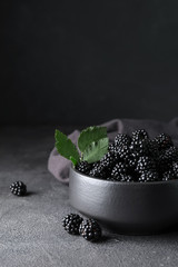 Fototapeta na wymiar Bowl with tasty blackberry on dark background