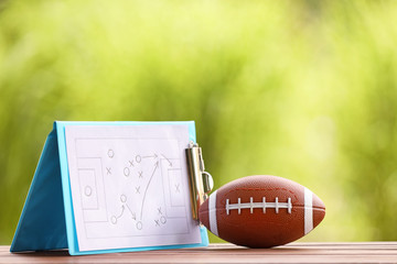 Rugby ball with scheme of football game on table outdoors