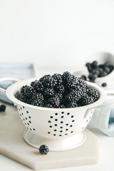 Fototapeta na wymiar Colander with ripe blackberry on white background