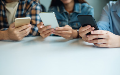 Group of young people using and looking at mobile phone while sitting together
