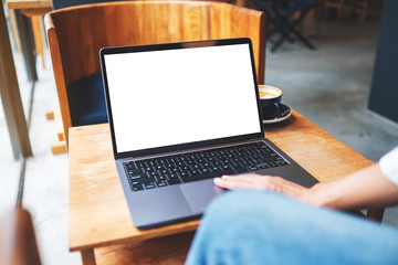Fototapeta premium Mockup image of a businesswoman using and touching on laptop touchpad with blank white desktop screen in cafe