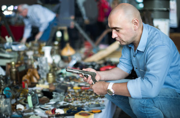 positive american adult man is looking antiquariat at the market of old things.