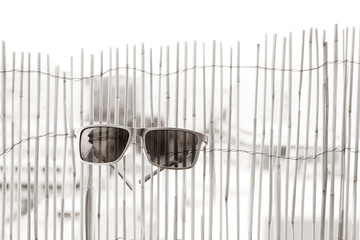 Classic model Sunglasses with metal frame and black lense hanging on bamboo fence. Selective focus 