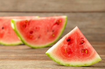 Fresh ripe striped sliced watermelon on grey wooden background.