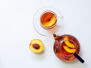 Fresh peach tea in a mug and glass teapot on a white background with copy space.