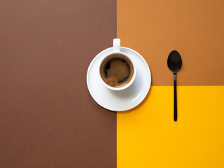 A cup of coffee with a spoon on brown paper background. Copy space.