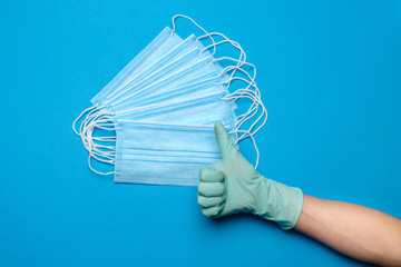 Human hand in protective glove and face protective masks isolated over blue background