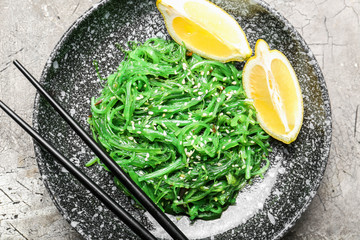 Plate with tasty seaweed salad on grey background