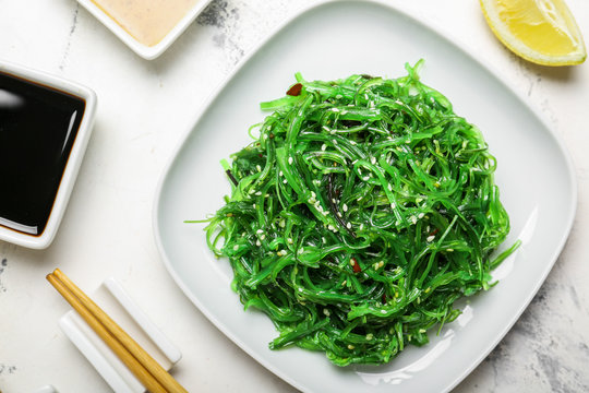 Plate with tasty seaweed salad on table