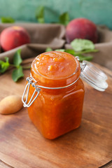 Jar with tasty peach jam on table