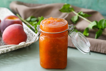 Jar with tasty peach jam on table