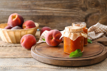 Jars of tasty peach jam on table