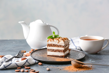 Plate with tasty tiramisu and tea on table