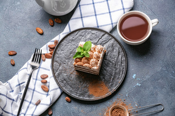 Plate with tasty tiramisu and tea on dark background