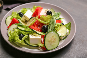 Plate with tasty cucumber salad on dark background