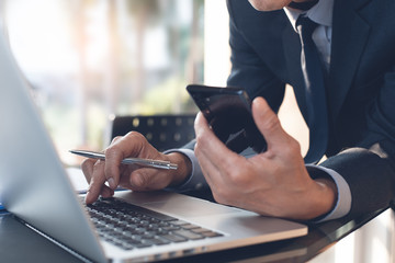 Fototapeta premium Businessman in black suit surfing the internet on laptop computer while working in office