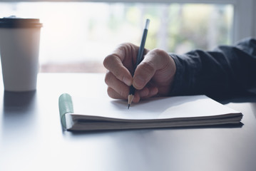 Close up of man hand writing on notepad with pencil side view