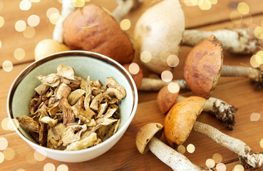 culinary, food and cooking concept - dried mushrooms in bowl on wooden background