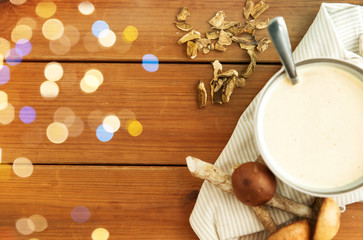 food cooking, eating and culinary concept - mushroom cream soup in bowl on wooden cutting board