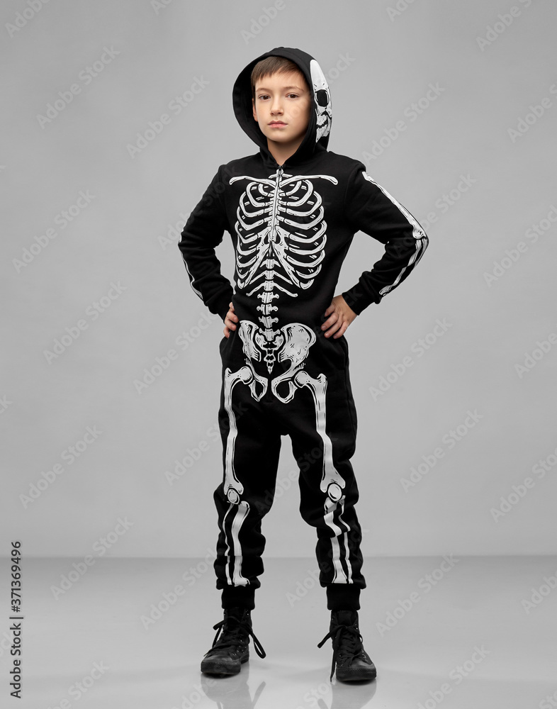 Wall mural halloween, holiday and childhood concept - boy in black costume with skeleton bones over grey background