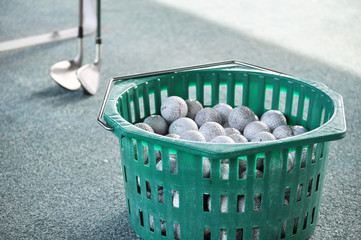 打ちっぱなし場のかごに入ったゴルフボールとクラブ