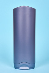 Gray shampoo bottle. Isolated on blue background.