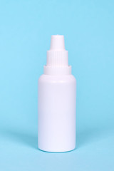 Nasal spray, drops in white bottle. Isolated on blue background.