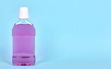 Purple mouthwash bottle, dental health care. Isolated on blue background, copy space template, banner.
