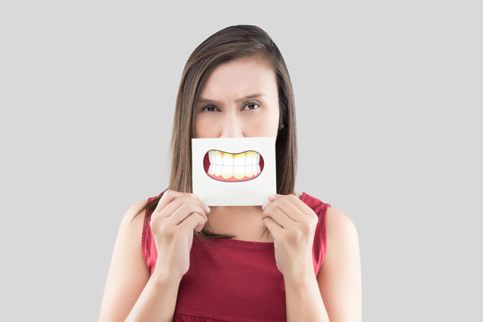 Asian woman in the red shirt holding a brown paper with the Dental plaque cartoon picture of his mouth against the gray background, Bad breath or Halitosis, The concept with healthcare gums and teeth