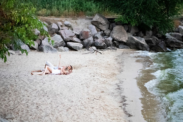 A young couple hugs passionately on the deserted sandy shore. Lifestyle of passionate newlyweds by the ocean. Love, passion and falling in love concept,