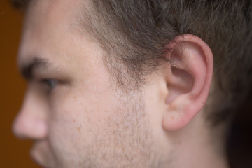 Fototapeta premium Side view of a man with uncropped hair. Adult man with short hair on his back. Adult man with a sloppy hairstyle and a neck overgrown with hair.