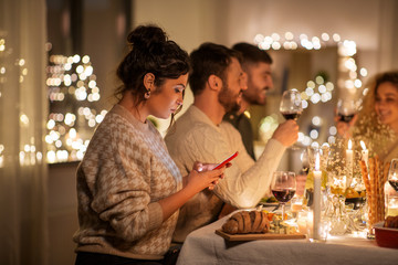 holidays and people concept - woman with smartphone at dinner party with friends at home