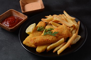 Traditional English Food - Fish and Chips. Fried fish filets and crispy French fries served with ketchup and homemade tarter sauce.