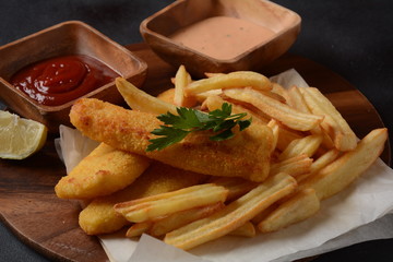 Traditional English Food - Fish and Chips. Fried fish filets and crispy French fries served with ketchup and homemade tarter sauce.