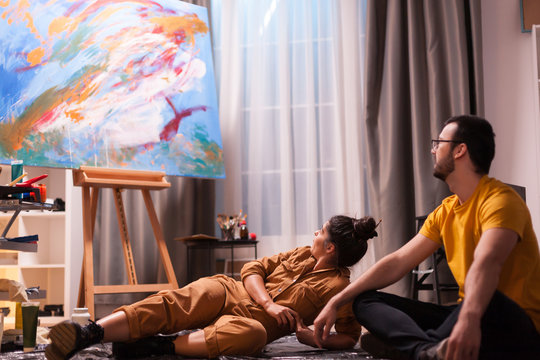 Painter and is partner having a conversation about abstract painting on large canvas. Modern artwork paint on canvas, creative, contemporary and successful fine art artist drawing masterpiece