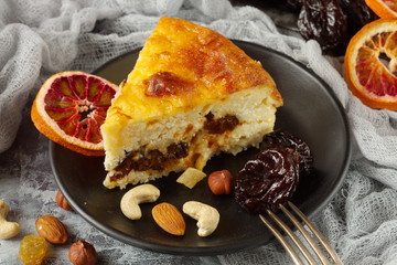 A piece of cottage cheese casserole from fresh cottage cheese is on a black plate. The recipe includes dried fruits,nuts. Eco-friendly, tasty, healthy food.