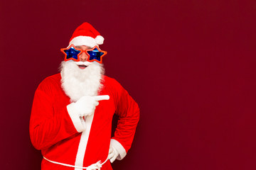 Portrait of stylish Santa in costume indicate aside forefinger at copy space