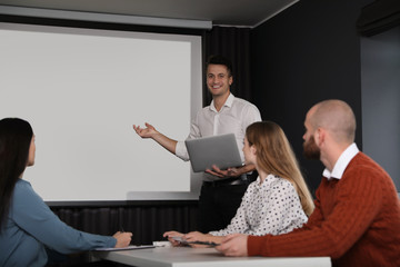 Business people listening to speaker in conference room with video projection screen