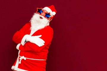 Portrait of positive young Santa look at camera red studio background with copy space cross hands on chest