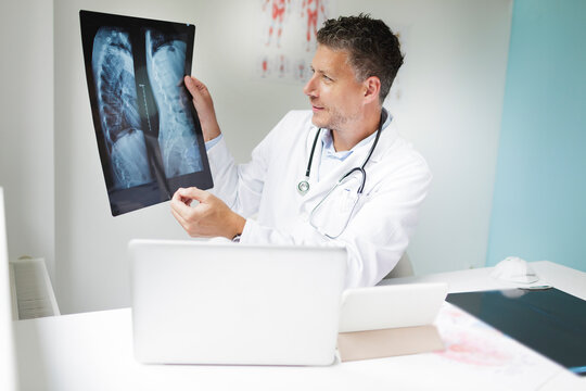 Doctor discusses X-ray image via video conference with his patient in his practice