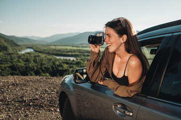 Young Traveler Woman on a Road Trip, Girl Enjoying Journey on Her Car, Making Photo on Retro Old Camera