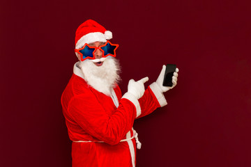 Portrait of satisfied santa claus use cell phone comment newyear posts reading news isolated over red background