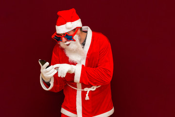 Portrait of satisfied santa claus use cell phone comment newyear posts reading news isolated over red background